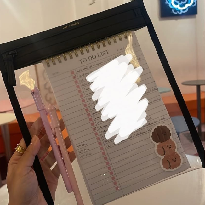 Hand holding a pen with a light effect over a to-do list on a lightbox.